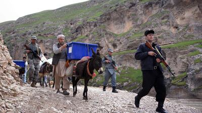 Afghan election workers are escorted by Afghan policemen as they use donkeys to transport election materials and ballot boxes to remote polling stations in the Kishindih district of Balkh Province in northern Afghanistan on April 3, 2014. Farshad Usyan / AFP