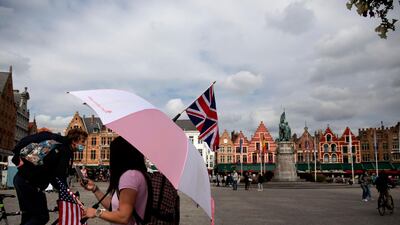 A tour operator stands under an umbrella with a British and American flag as she waits for customers in the centre of Bruges, Belgium. AP Photo