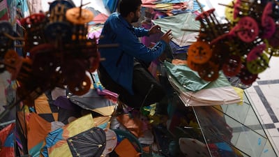 A kite vendor cuts tissue paper as he makes a kite in a shop in Shor Bazaar in Kabul.