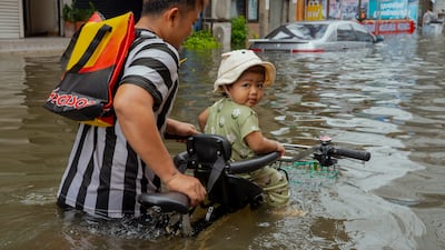 A child is led through floodwater on a bicycle on Ramkhanghaeng Road in Bangkok, Thailand. Nearly 300mm of rain have fallen since Thursday. Getty Images