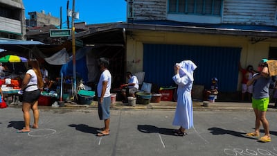 People stand on designated spots to maintain social distancing at a market in Manila. AFP