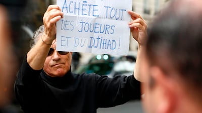 A protester holds a placard with a message in French that says "Qatar buys everything, some players and some Jihad", as the entourage of Brazilian footballer Neymar arrives at a hotel in Paris on August 4, 2017 following the Brazilian footballer's world record transfer for 222 million euros from Barcelona to Paris Saint-Germain. Benjamin Cremel / AFP