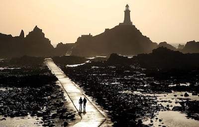 A couple walk on the causeway leading to the Corbiere lighthouse in Jersey, Channel Islands. Getty Images