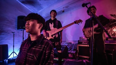 In a photo taken on November 10, 2019 members of 'post hardcore' metal band 'Monsters Dive' (L-R) Chu Yeonsik, Kim Daesik, and Dominic Jin rest betweet songs during their set at a venue in Seoul. Head-banging away in the shadow of a multi-billion-dollar K-pop industry, South Korea's axe-wielding heavy metal bands shred a modest trail of destruction. And in a society where conformity is widely expected, the mosh pit masters are as clean-cut as any average Seoul citizen. - TO GO WITH: SKorea music social metal, by Ed JONES and Yelim LEE / AFP / Ed JONES / TO GO WITH: SKorea music social metal, by Ed JONES and Yelim LEE