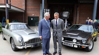 The royal poses with Daniel Craig in front of two Aston Martins that will appear in the films. Getty Images