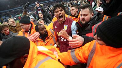 Aston Villa's Tyrone Mings celebrates with fans on the pitch. Reuters