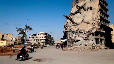 Syrians ride their motorcycles past a damaged building in the Syrian city of Raqqa on October 18, 2018. AFP