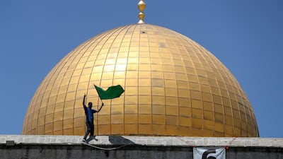 A man holds a Hamas flag while standing on the Dome of the Rock in Jerusalem. Reuters