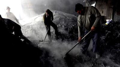 Workers spread charcoal for cooling in the West Bank village of Yabed. Around 400 kilns are in operation in the West Bank, producing 1,600 tonnes of charcoal every month most of which is sold to Israel. Alaa Badarneh / EPA