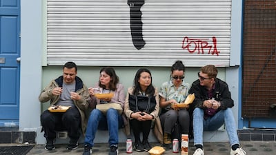 Revellers at London's Notting Hill Carnival rest in front of an anti-knife crime message. EPA