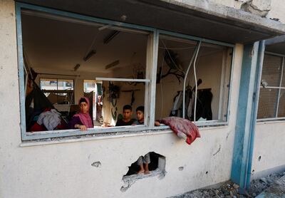 Palestinians stand near the damaged windows of a classroom in a UNRWA school, after the air strike on a neighbouring house to the school in Khan Younis, in the southern Gaza Strip. Reuters