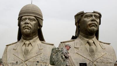 US soldiers stroll past two bronze busts of former Iraqi president Saddam Hussein. Hadi Mizban / AP