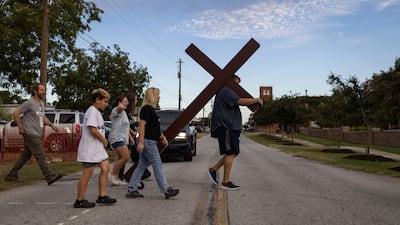 A man carries a large cross to a vigil for the Apalachee High School shooting at Jug Tavern Park in Winder, Georgia. AFP