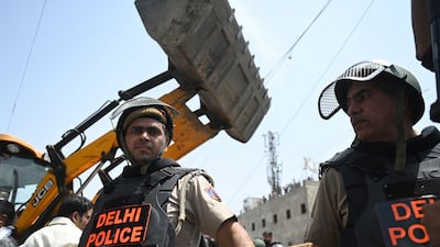 Police on guard as a bulldozer demolishes 'illegal' structures in a residential area of Jahangirpuri in New Delhi on April 20, 2022. AFP