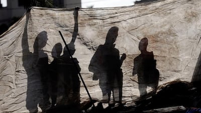 Palestinians wait behind a plastic sheet separating them from the crate of a destroyed house following an Israeli military strike in the center of Gaza City. Thomas Coex / AFP