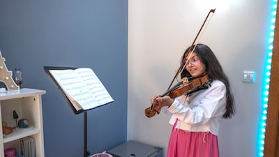 Celina, 11, plays the violin in her room.
