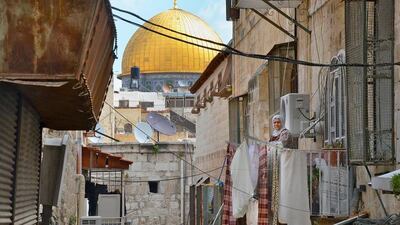 A Palestinian woman stands on her balcony opposite the Sub Laban family home with the Dome of the Rock in the background. Kate Shuttleworth for The National