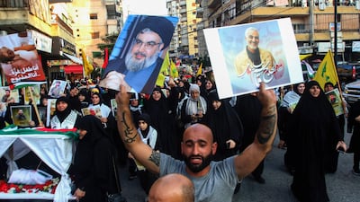 A demonstrator holds placards depicting Hezbollah chief Hassan Nasrallah and Iranian general Qassem Suleimani during a march in Sidon, Lebanon, last Saturday. AFP