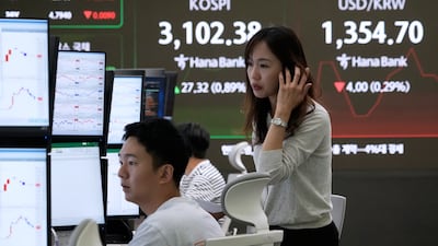 Currency traders watch monitors as a screen behind them shows the Korea Composite Stock Price Index. Asian markets closed out the week mixed. AP