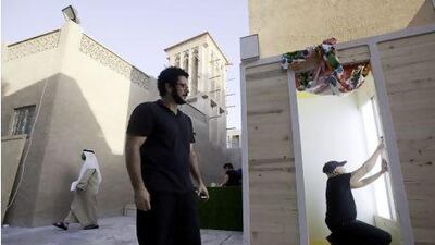 Suresh Natarajan, right, takes his picture inside a photo booth which is part of a project by Camille Mallat, centre, at the Sikka Art Fair in the Bastakiya District of Dubai. Jaime Puebla / The National