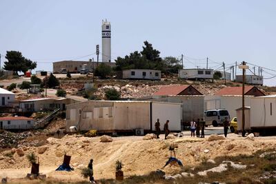 Israeli settlers and soldiers stand at the entrance of the Israeli settlement of Ahya near the West Bank village of Jalud. AFP