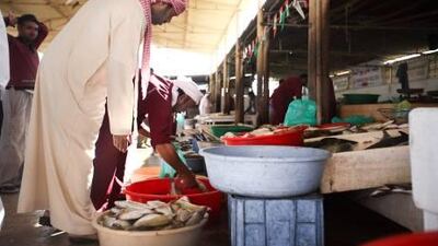 An Umm Al Qaiwain man looks through the replenished stock at the emirate's main fish market as prices stabilise and business picks up.