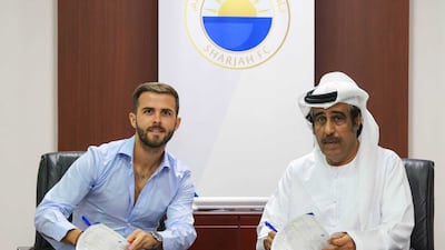 Miralem Pjanic puts pen to paper on his contract with Sharjah. Photo: Sharjah FC