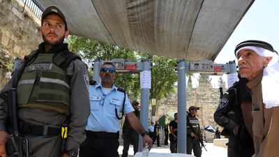 Israeli police officers stand guard next to newly installed metal detectors as a Palestinian man stands nearby at the entrance to the compound known to Muslims as Noble Sanctuary and to Jews as Temple Mount, in Jerusalem's Old City. Ammar Awad / Reuters