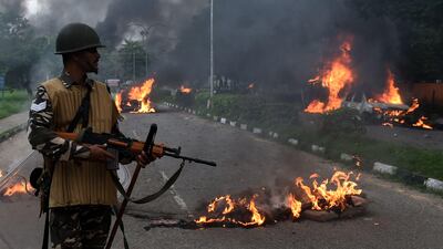 Indian security personnel look at burning vehicles set alight by rioters. Money Sharma / AFP Photo