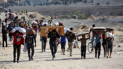 Palestinians carry bags, wooden pallets and empty cardboard boxes as they leave a food distribution point run by the US and Israeli-backed Gaza Humanitarian Foundation group, near the Netsarim corridor in the central Gaza Strip on October 5. A senior Hamas official on October 5 said the Palestinian militant group is eager to reach an agreement to end the war and implement a prisoner swap with Israel, as negotiators converge in Egypt for talks. AFP