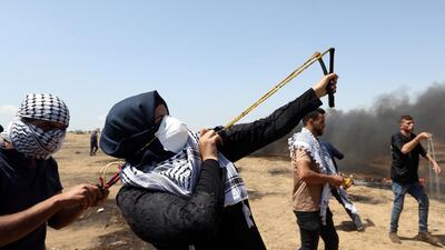 A female demonstrator uses a slingshot to hurl stones at Israeli forces during the final week of border protests in the southern Gaza strip. Ibraheem Abu Mustafa / Reuters