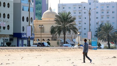 A man walks on the beach on the Ajman corniche. Chris Whiteoak / The National