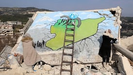Two Syrian artists paint a remainder of a wall of a collapsed building in Al Milan village of Idlib city in Syria. EPA