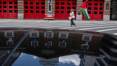 A demonstrator carrying a Palestinian flag walks past a fire station in Washington, US. AP
