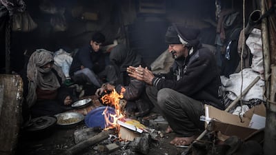 Members of a Palestinian family warm themselves by a fire during a cold weather spell in an impoverished neighbourhood on the outskirts in Gaza City. AFP
