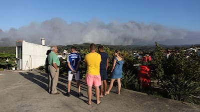 People keep their distance from a nearby forest fire in the Landal district of Caldas da Rainha in Portugal. AP