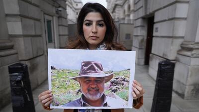 Roxanne Tahbaz holds a picture of her father Morad Tahbaz, who is jailed in Iran, at a protest outside the Foreign Office in London. PA