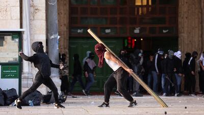 Palestinian youths hurl stones towards police at a gate to Al Aqsa Mosque compound. Reuters