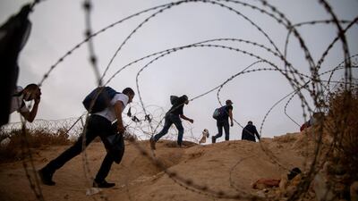Palestinian labourers cross illegally into Israel from the West Bank through an opening in a fence, south of the West Bank town of Hebron. AP