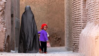 An Afghan woman walks with a child in the old city of Herat province, Afghanistan.. REUTERS