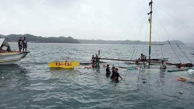 In this photo provided by the Philippine Red Cross, rescuers stand beside the remains of the M/B Chichi ferry boat after it capsized due to bad weather. Philippine Red Cross via AP