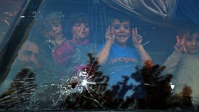 The children of Jaish Al Islam fighters look out of the window of a bus after their evacuation from the rebel stronghold of Douma in Eastern Ghouta / AFP