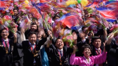 Participants wave flowers as they march past a balcony from where North Korea's leader Kim Jong Un was watching, during a mass rally on Kim Il Sung square in Pyongyang. AFP