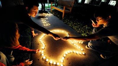 Chinese exchange students from nearby De Anza College use candles to create the Apple logo and Steve Jobs' last name in Chinese characters at a makeshift memorial for Steve Jobs at the Apple headquarters in Cupertino, California.