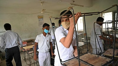 Pupils wearing face masks arrange desks in a classroom after their school was reopened in Colombo. AFP