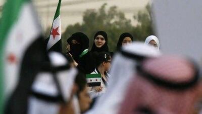 Kuwaiti citizens and Syrians residents hold up the adopted Syrian revolutionary flag during a protest in front of the Syrian Embassy in Kuwait City on Saturday following the reported killing of 92 people, including 32 children, in the Syrian town of Houla.
