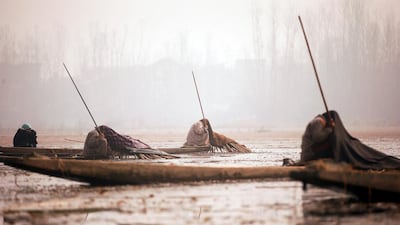 Kashmiri fishermen on Anchar Lake cover their heads with blankets on a cold day in Srinagar. Danish Ismail / Reuters