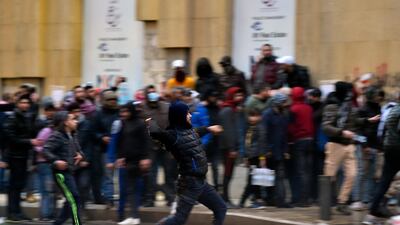 Anti-government protesters hurl stones at riot police behind a barrier during a rally outside of the Lebanese parliament in Beirut. EPA