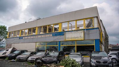 Parts of a roof hang over the facade of a car dealership. AP Photo