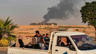 Civilians ride a pickup truck as smoke billows following Turkish bombardment on Syria's northeastern town of Ras Al Ain. AFP